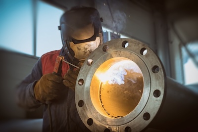 Here a welder is fusing a heavy-duty pipe and pipe fitting with one another, a suitable application for a 7018 stick welding electrode.