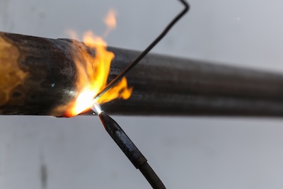 Applying filler material by positioning the rod in front of the flame.